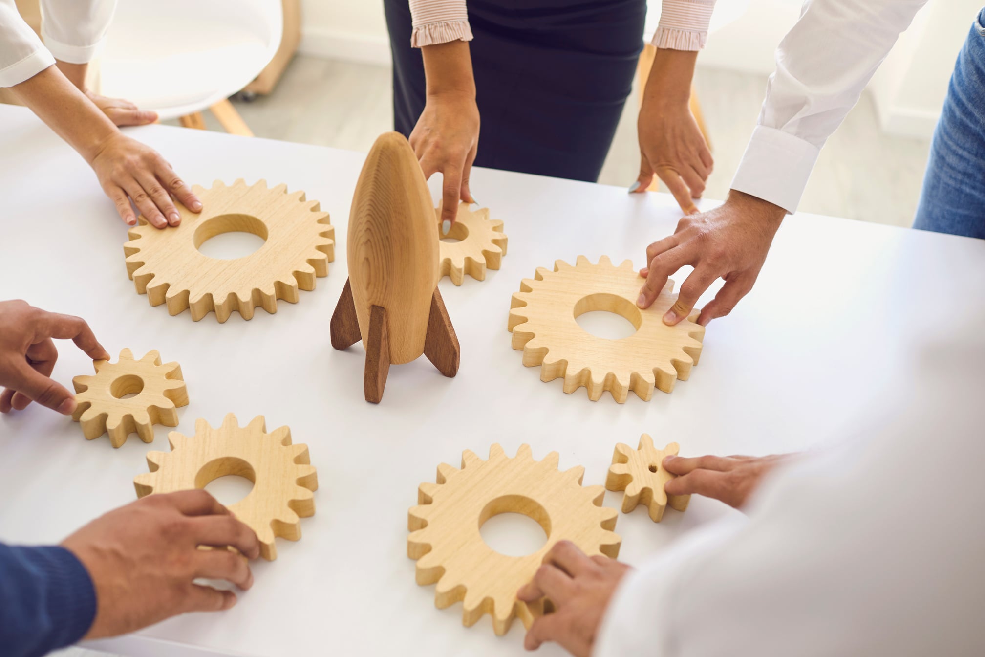 Businesspeople around Office Table with Rocket and Cogwheels Deciding on Company Strategy